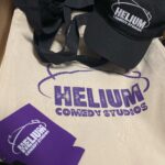 Helium Comedy Club branding appears on light and dark apparel in this small photograph from the original gallery.