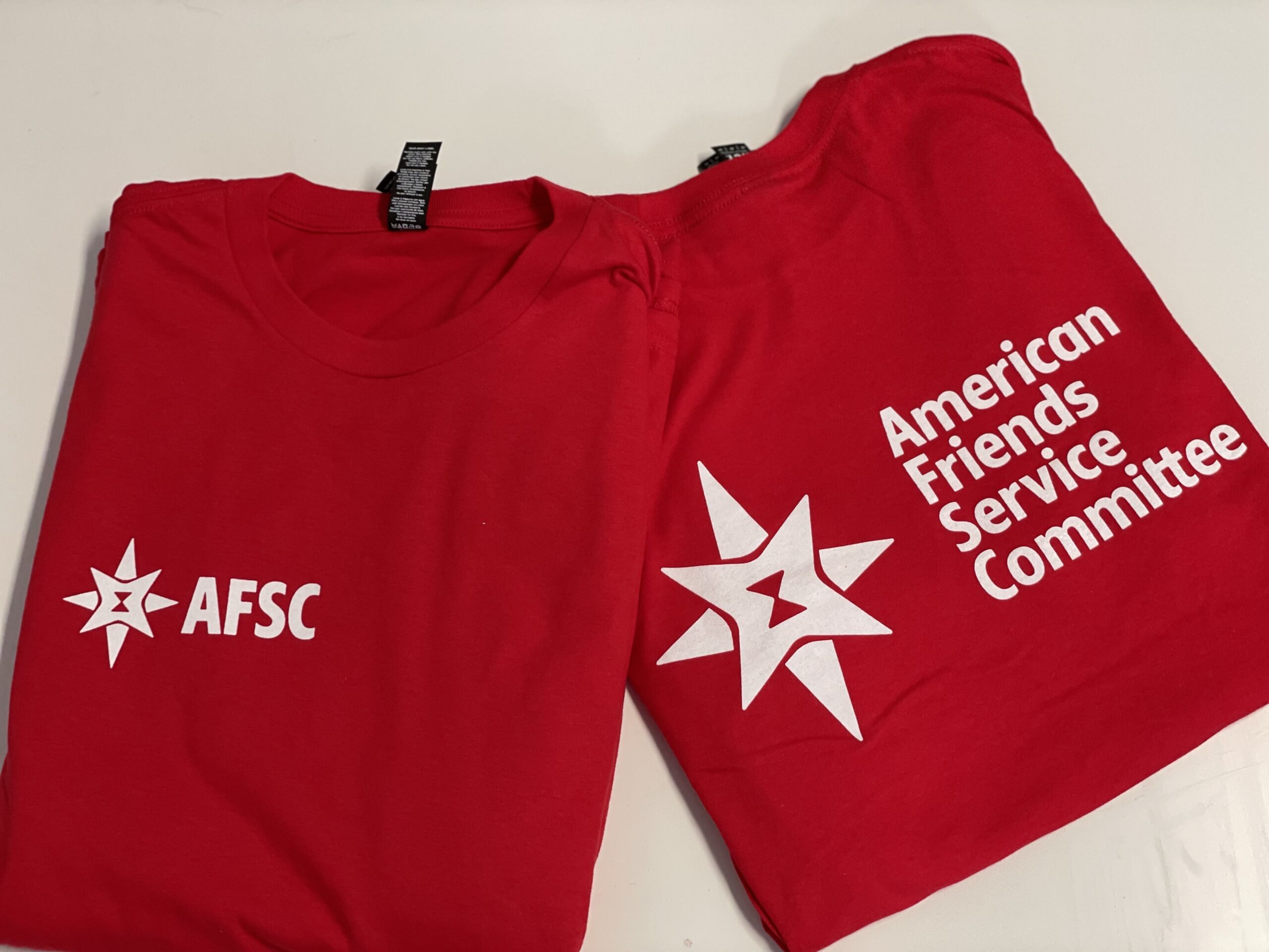 Red garments show the AFSC name and star emblem in crisp white, with different print placements arranged side by side.