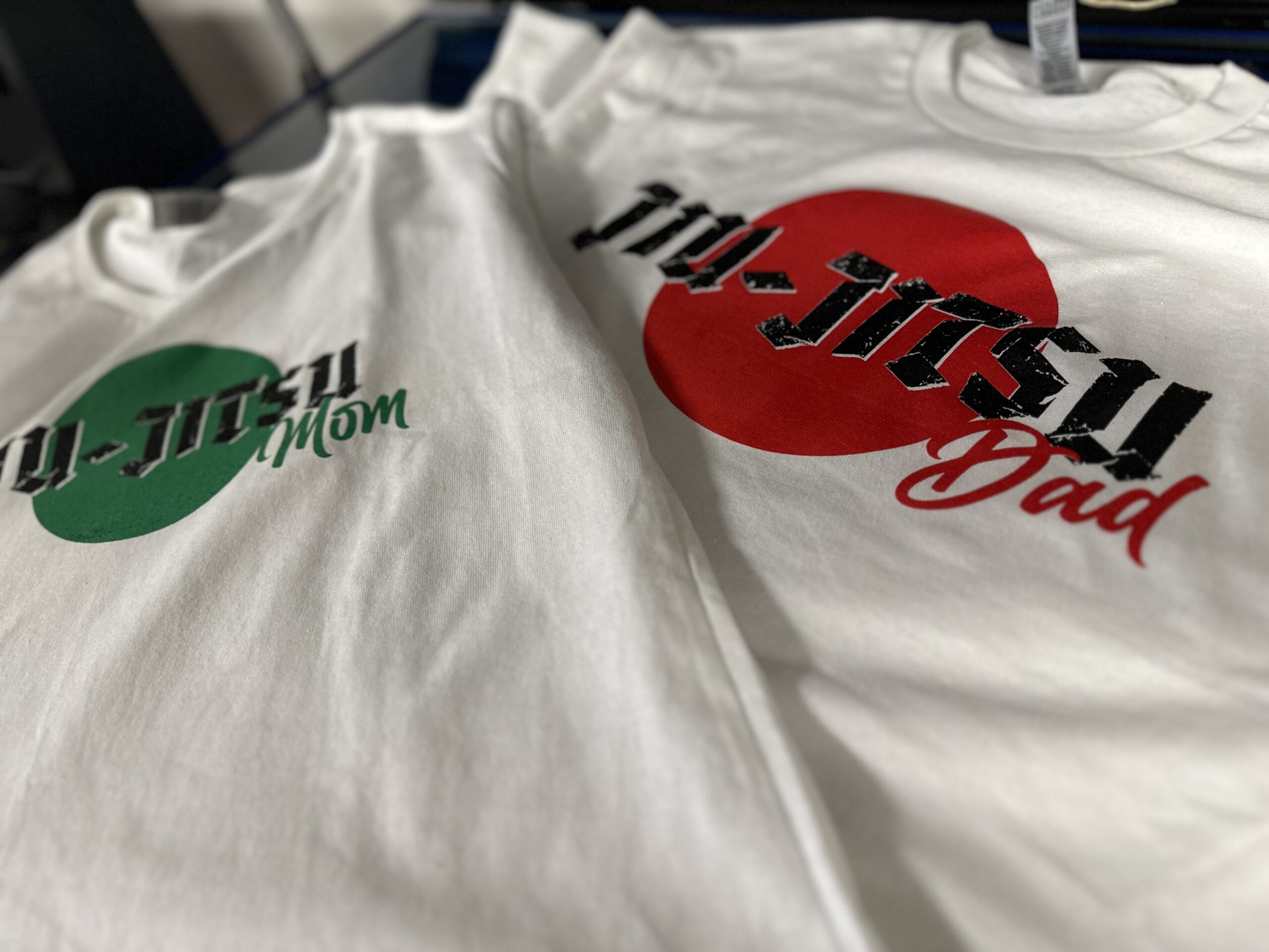 Light-colored tees pair black lettering with red and green circular graphics. One design reads “The Japan Dad.”
